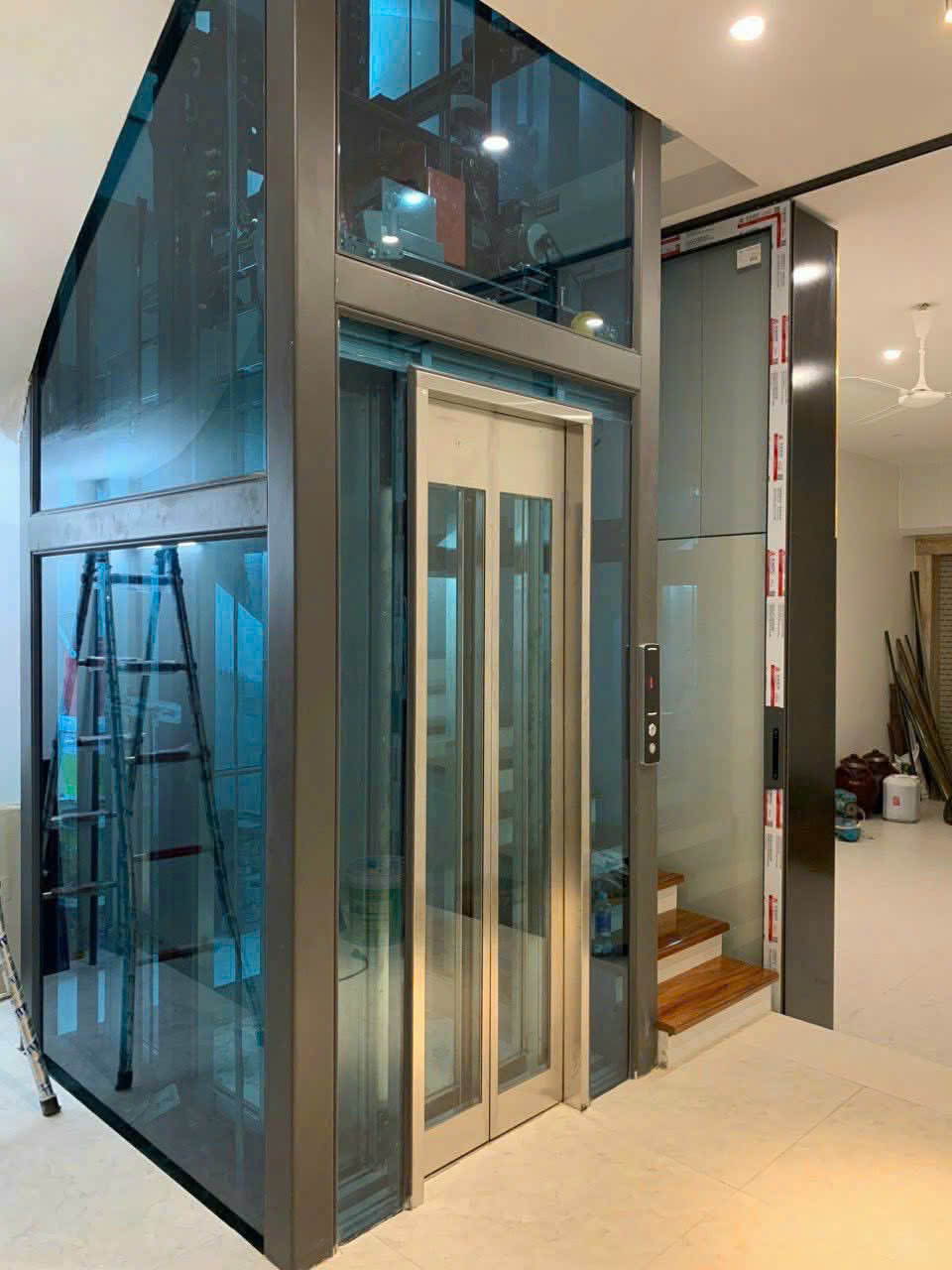 Thang máy gia đình vách kính khung nhôm đang lắp đặt trong nhà hiện đại